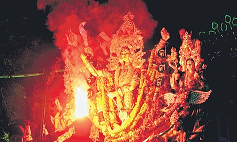 A man performs arati of Maa Budhi Thakurani during immersion procession, in Cuttack