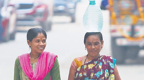 A construction worker carries a water can on her head as she returns home after work in Hyderabad.