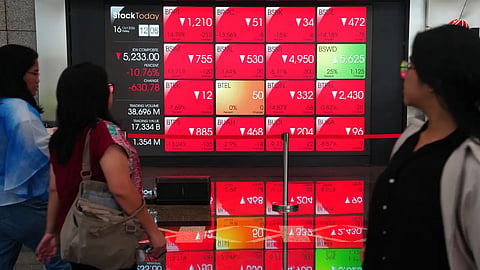 Onlookers walk past a screen displaying stock prices at the Indonesia Stock Exchange in Jakarta on Friday
