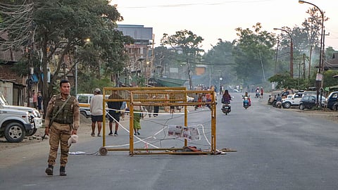 In this photo from Oct. 21, 2026, a security person stands near a barricade during a 48-hour statewide shutdown over the killing of three civilians in Imphal East on Wednesday.