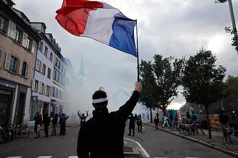 A protester holds a French flag during a demonstration against rising living costs in Strasbourg, France, Saturday, Oct. 24, 2026.