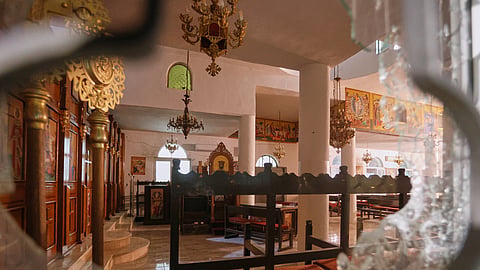 The interior of a Greek Orthodox church is seen through a shattered window hours after gunmen opened fire during a funeral in Hamoud village, in Jordan's Karak governorate, Friday, Oct. 23, 2026.
