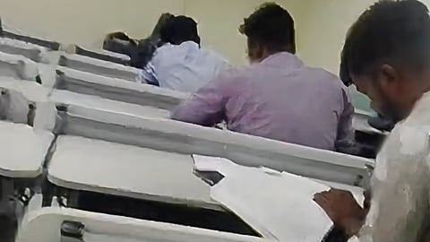 A videograb shows a student copying from books at a KSOU exam centre in Shivamogga.