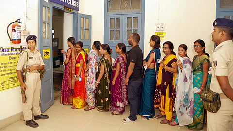 Voters wait in a queue at a polling station as they arrive to cast their vote for the Graduate and Patna Teacher constituencies of the Bihar Legislative Council (MLC), in Patna, Friday, Oct. 23, 2026.