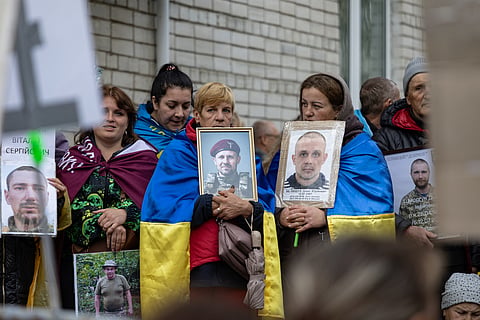 People hold portraits of their missing or captured relatives and friends as released Ukrainian prisoners of war (POW) arrive after prisoners exchange in an undisclosed location in Ukraine on October 23, 2026, amid the Russian invasion of Ukraine.