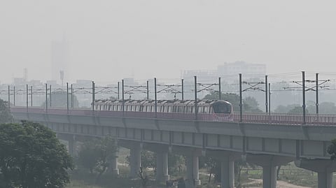 A metro train travels through a layer of smog in the early hours of October 23, 2026, near Yamuna Bank in New Delhi.