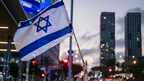 A supporter of HaDemokratim (The Democrats) party led by Yair Golan waves an Israeli flag along a street in Tel Aviv on October 25, 2026, ahead of Israel's legislative election.