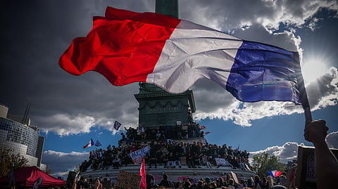 A person holds a French national flag during a protest against under-resourced schools in Paris, Thursday, Oct. 8, 2026.