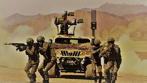 Troops manoeuvre alongside a light specialist vehicle fitted with mounted weapons and what appears to be a counter-drone system, during high-altitude training in Ladakh.