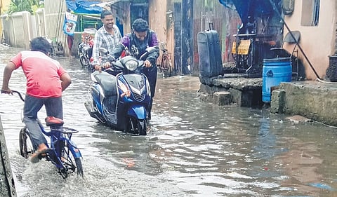 Two men push their scooter along a waterlogged road at Hatipokhari in Cuttack 