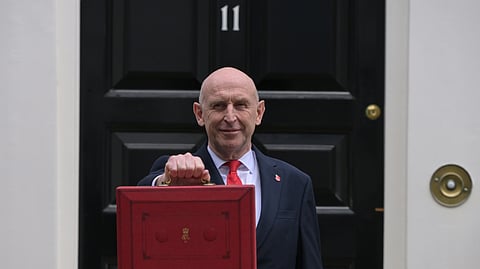 Britain's Chancellor of the Exchequer John Healey poses on the doorstep of 11 Downing Street with the ministerial red box before heading to the House of Commons to deliver the budget statement in London, Wednesday, Oct. 28, 2026.