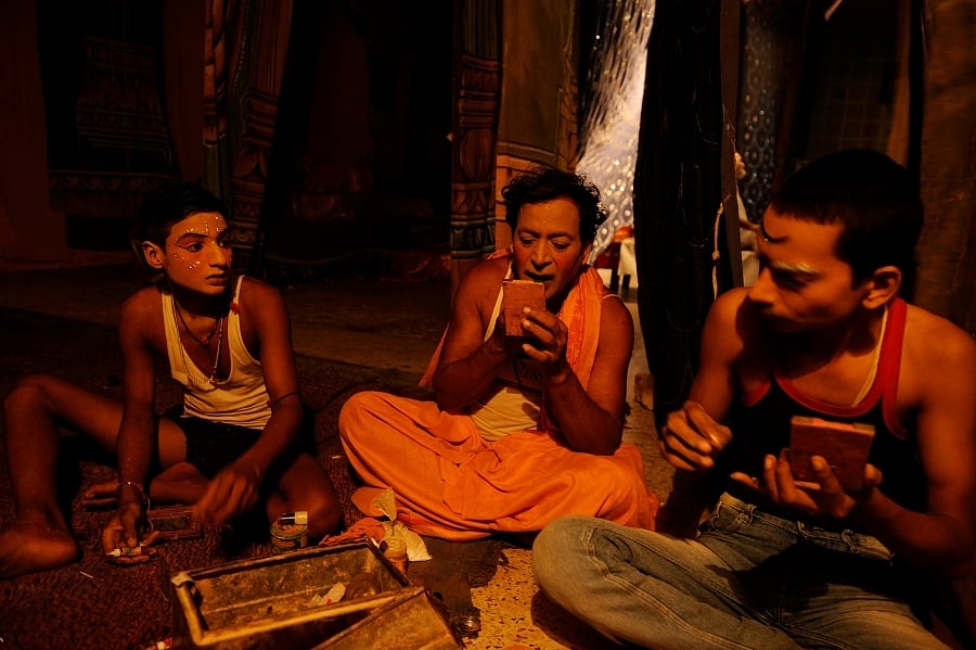 In a makeshift greenroom lit in harsh yellow, Ramkatha actors prepare to disguise themselves as Ramayana characters. They cannot afford to engage professional makeup artists, so they teach themselves. 