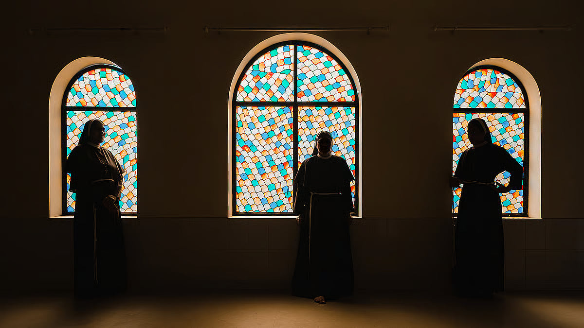 Nuns next to stained glass windows of a church. Photo: Isaac Nico