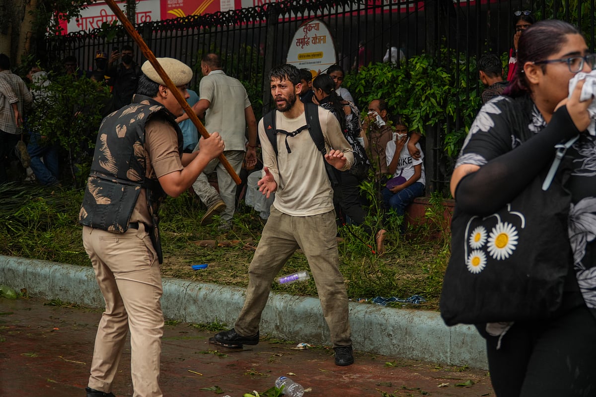 A policeman rains lathi blows on a protester near Parliament.