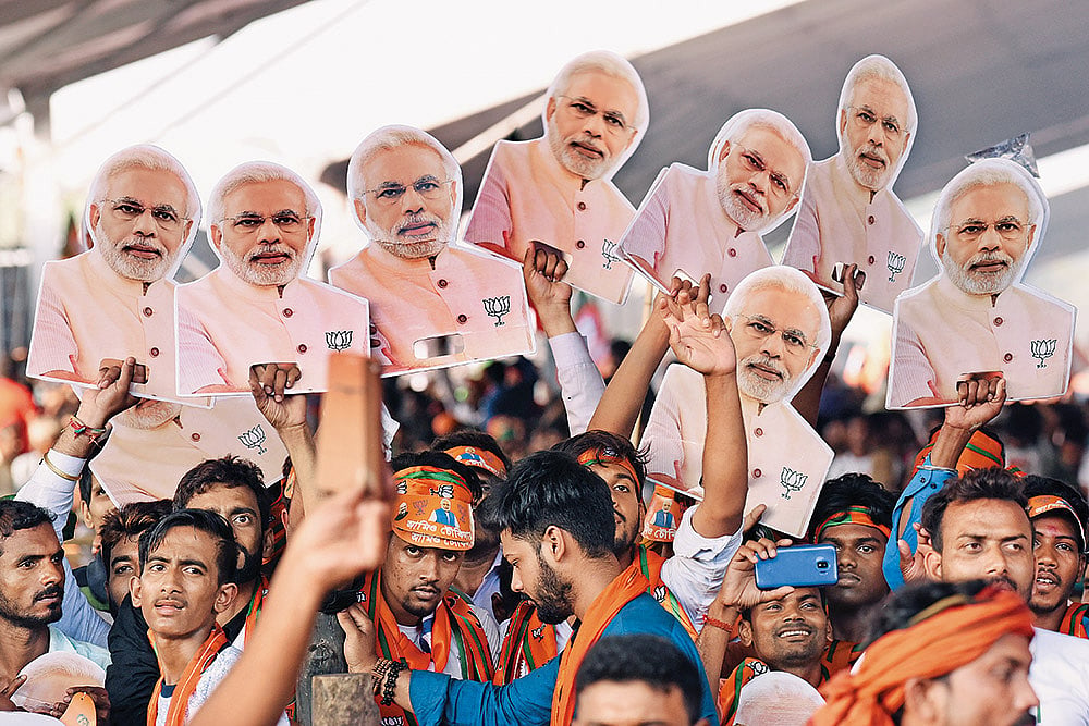 Photo: Getty Images : Politics of Polling: BJP supporters hold placards of PM Modi during an election rally