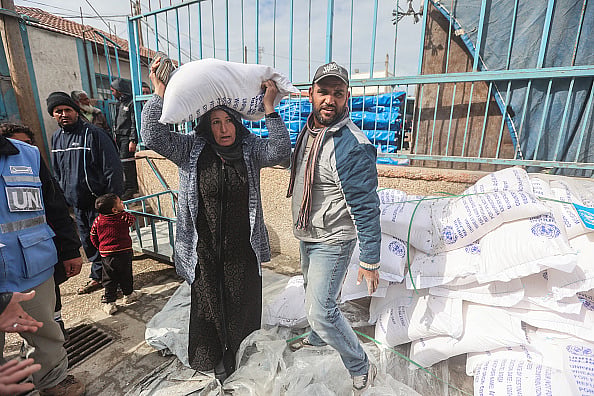 Palestinians carry the flour they received from UNRWA.