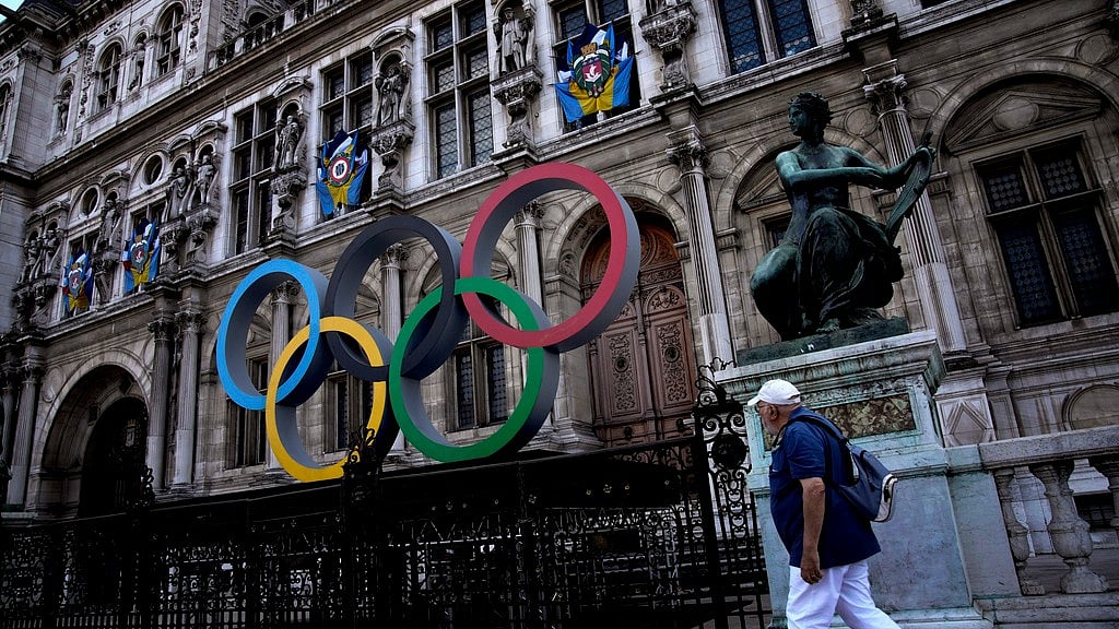 A man walks past the Olympic rings in front of the Paris City Hall one year until the Paris 2024 Olympic Games opening ceremony, Wednesday, July 26, 2023.  - (AP Photo/Christophe Ena, File)