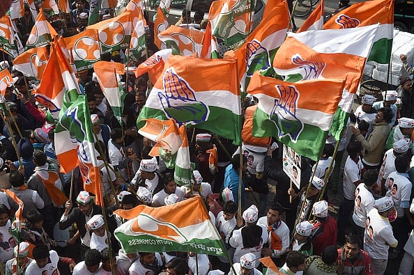 Congress party supporters wave party flags during an election roadshow with party leader Rahul Gandhi - Getty Images