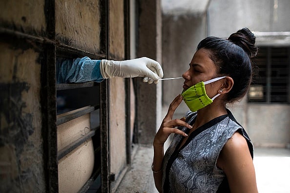 Health official collects a swab sample from a woman to test for the COVID-19 coronavirus at a temporary free testing facility set up in a school after authorities eased restrictions imposed as a preventive measure against the spread of the COVID-19 coronavirus, in New Delhi on June 19, 2020. (Representational Image) - (Photo by XAVIER GALIANA/AFP via Getty Images) 