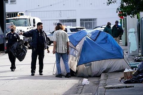 A City of Miami police officer talks with a homeless person, prior to a cleaning of the street, Tuesday, Nov. 16, 2021, in Miami. 