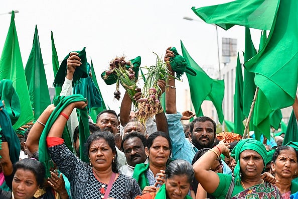 (Photo by Manjunath Kiran via Getty) :  Farmers from various districts of Karnataka hold green flags and crops as they take part in a protest rally staged against the Bharatiya Janata Party (BJP) led central governments over the inadequate distribution of compensation to the farming community victims of natural disasters such as flood and drought.