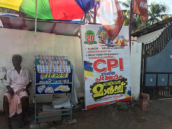 Getty Images : Man selling lottery tickets by a poster for the Communist Party of India in the city of Thiruvananthapuram (Trivandrum), Kerala