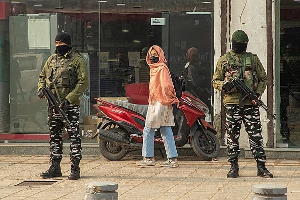 Getty Images : A Kashmiri girl looks on as paramilitary personnel stand guard along a road in Srinagar ahead of SC's verdict on Article 370.