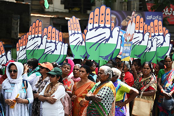 Getty Images : Congress party supporters hold the party's symbol during a roadshow for Mansoor Ali Khan, election candidate for Bengaluru central