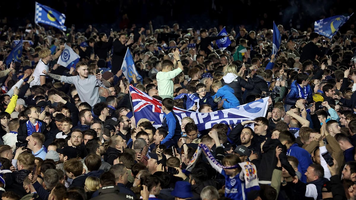 Steven Paston/PA : Portsmouth fans celebrate on the pitch after their team secured promotion.