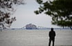In Key Bridge Collapse, Baltimore Lost A Piece Of Its Cultural Identity AP : A person views from Fort McHenry a container ship as it rests against the wreckage of the Francis Scott Key Bridge.