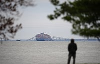 In Key Bridge Collapse, Baltimore Lost A Piece Of Its Cultural Identity AP : A person views from Fort McHenry a container ship as it rests against the wreckage of the Francis Scott Key Bridge.
