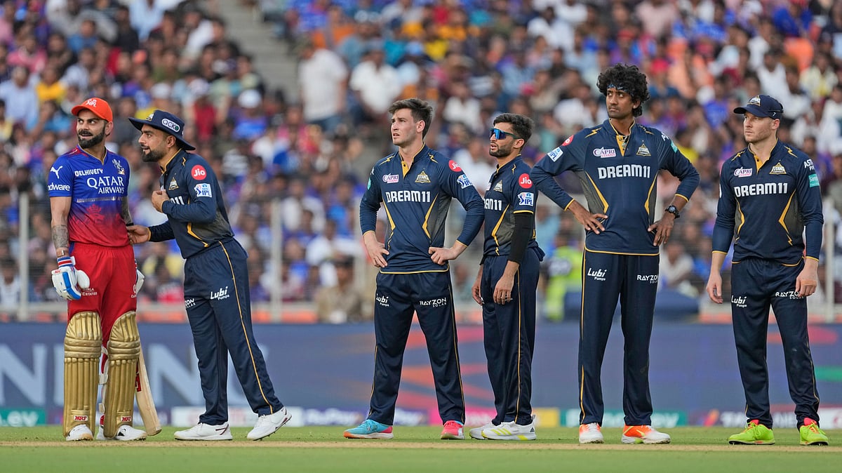 AP Photo /Ajit Solanki : Gujarat Titans' Rashid Khan, second left, talks to Royal Challengers Bengaluru's Virat Kohli as they wait for the third umpires's decision during the Indian Premier League cricket match between Gujarat Titans and Royal Challengers Bengaluru in Ahmedabad.