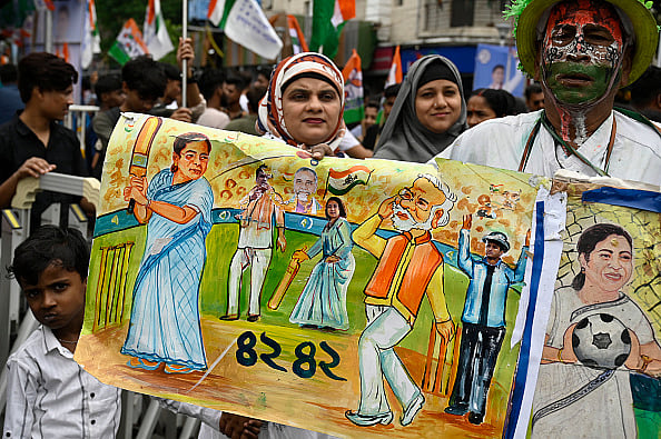 Samir Jana/Hindustan Times via Getty Images : An All India Trinamool Congress (AITC) supporter holds a poster during a rally before nomination file for General Election 2024 at Hazra on May 10, 2024 in Kolkata, India