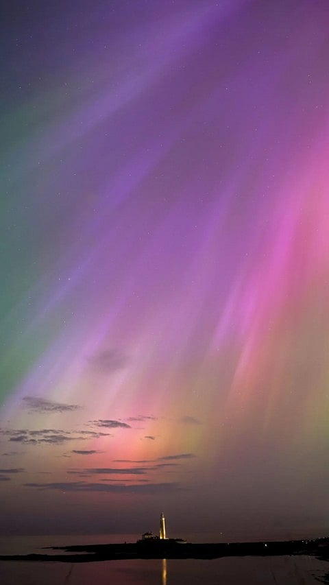 Northern Lights Glow On the Horizon At St. Mary's Lighthouse in Whitley Bay on the North East coast, England.