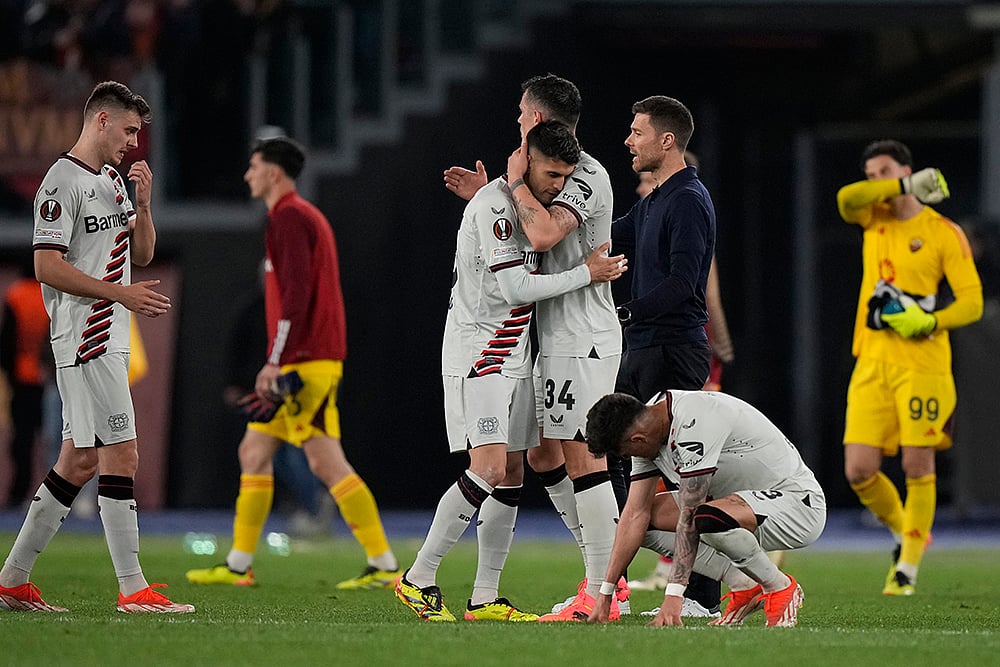 Leverkusens head coach Xabi Alonso, right, congratulates players