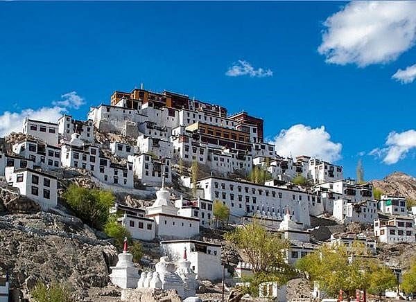 Thikse Monastery, a serene white structure nestled on a picturesque hillside.