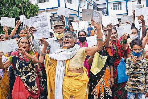 People show their ration cards during a protest against the state and the central government
