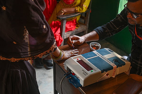 Kabir Jhangiani/NurPhoto via Getty Images : An election official is putting ink on the finger of a woman who is casting her vote at a polling station during the third phase of the Indian General Elections in Hathras district, Uttar Pradesh, India, on May 7, 2024