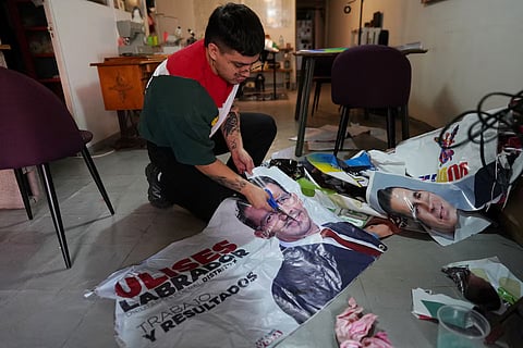 Camilo Morales cutting a vinyl political ad to create a designer tote bag.