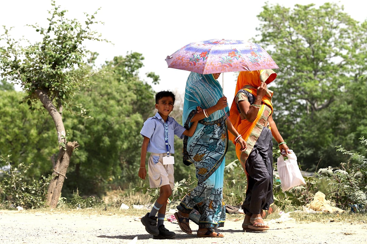 Suresh K Pandey/Outlook : A woman holding umbrella in her hand to protect herself and her child from the heat