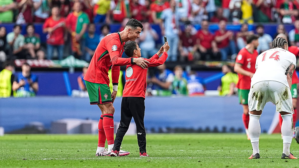 Cristiano Ronaldo poses for a photo with a young pitch invader.