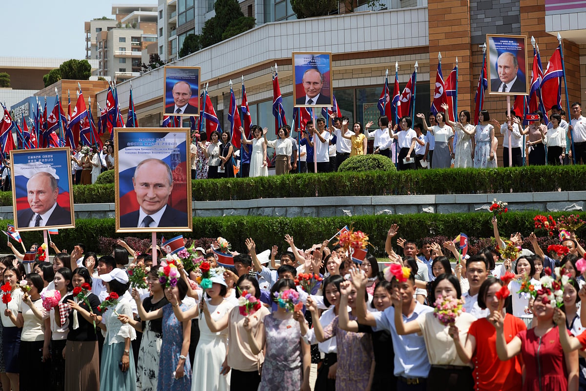 AP : People, holding portraits of Russian President Vladimir Putin, greet and applaud as a motorcade with Russian President Vladimir Putin and North Korea's leader Kim Jong Un move past in a street in Pyongyang, North Korea, Wednesday, June 19, 2024