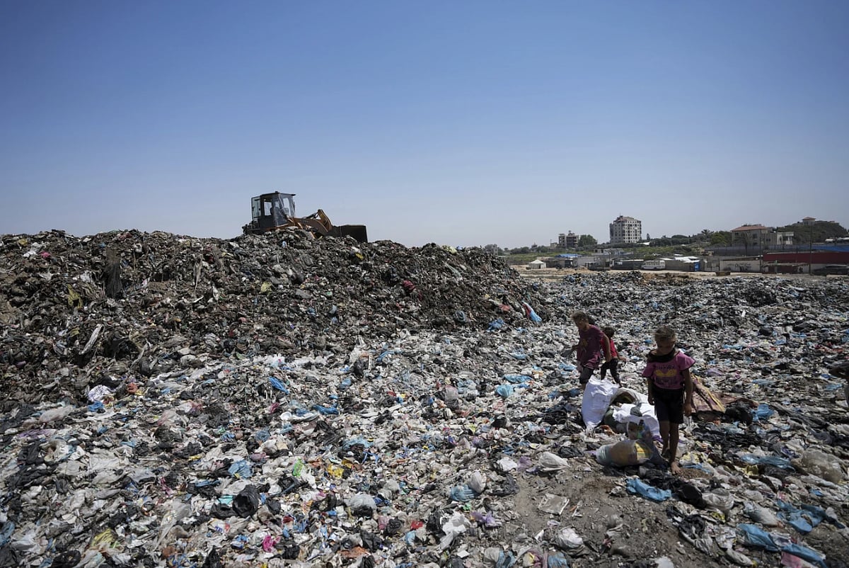 AP : Children in sandals trudge through water contaminated with sewage and scale growing mounds of garbage in Gaza's crowded tent camps for displaced families |