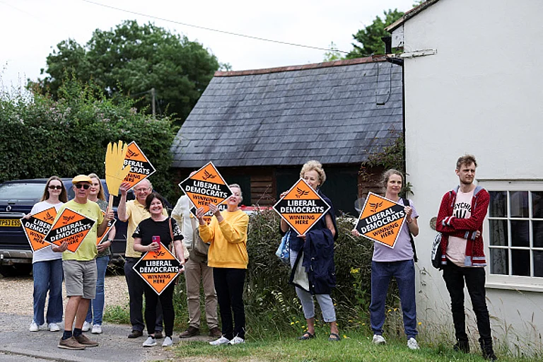 People hold Liberal Democrat signs outside Braishfield primary school as British Prime Minister and Conservative Party leader Rishi Sunak makes a visit as part of a Conservative general election campaign event in Romsey, Hampshire, southern England on July 3, 2024. - Getty Images