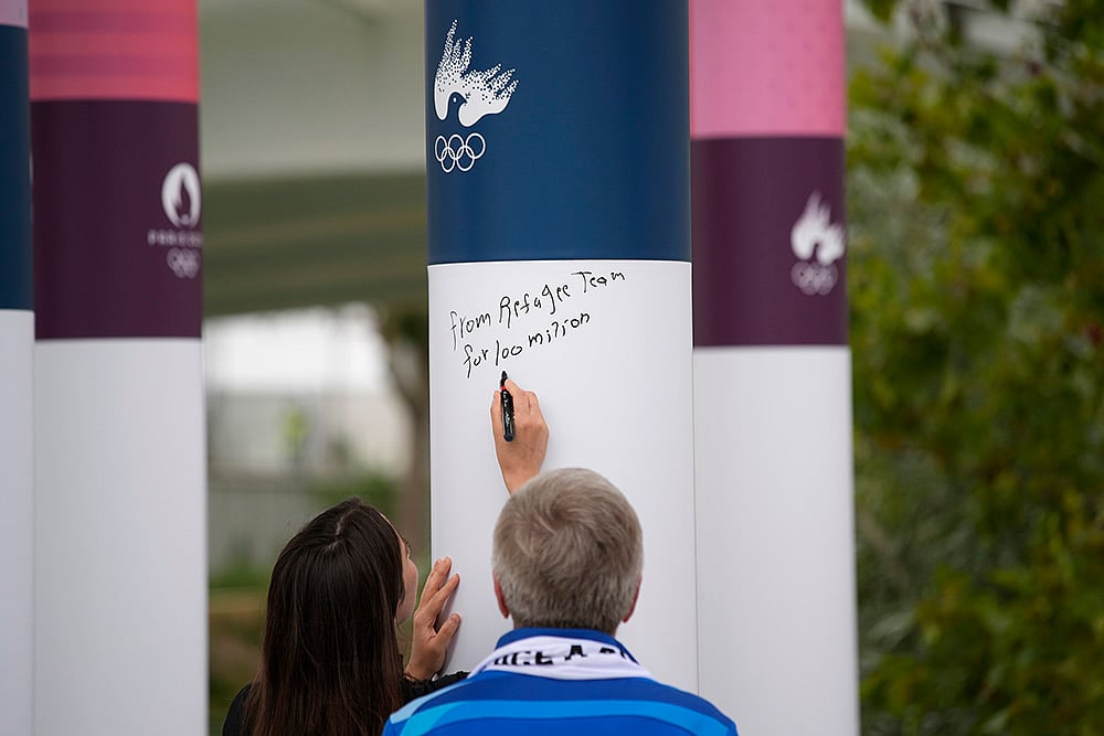 Refugee Olympic Team Muna Dahouk signing  Truce wall at 2024 Paris Olympic Village_1