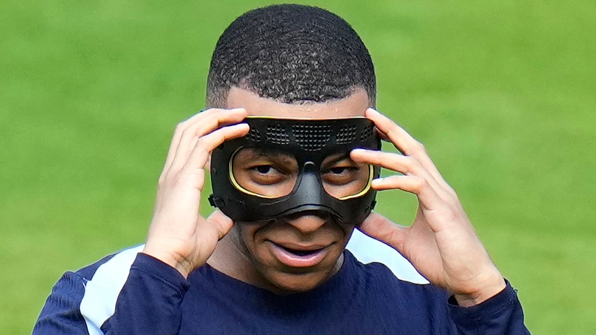 FILE - France's Kylian Mbappe gestures as he adjusts his face mask during a training session in Paderborn, Germany, on June 27, 2024. Kylian Mbappé has had more masks than goals at Euro 2024. Widely regarded as the heir to Lionel Messi and Cristiano Ronaldo as soccer's biggest icon, the France striker is struggling with his peripheral vision due to the protective face covering he has been fitted with since breaking his nose at the start of the European Championship.  - (AP Photo/Hassan Ammar)