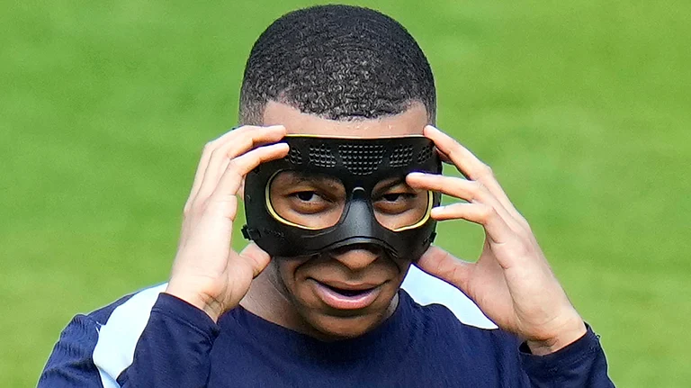 FILE - France's Kylian Mbappe gestures as he adjusts his face mask during a training session in Paderborn, Germany, on June 27, 2024. Kylian Mbappé has had more masks than goals at Euro 2024. Widely regarded as the heir to Lionel Messi and Cristiano Ronaldo as soccer's biggest icon, the France striker is struggling with his peripheral vision due to the protective face covering he has been fitted with since breaking his nose at the start of the European Championship. - (AP Photo/Hassan Ammar)