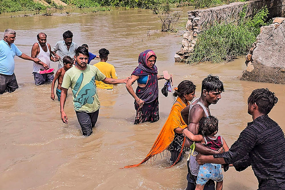 People wade through floodwater after breach in Munak canal