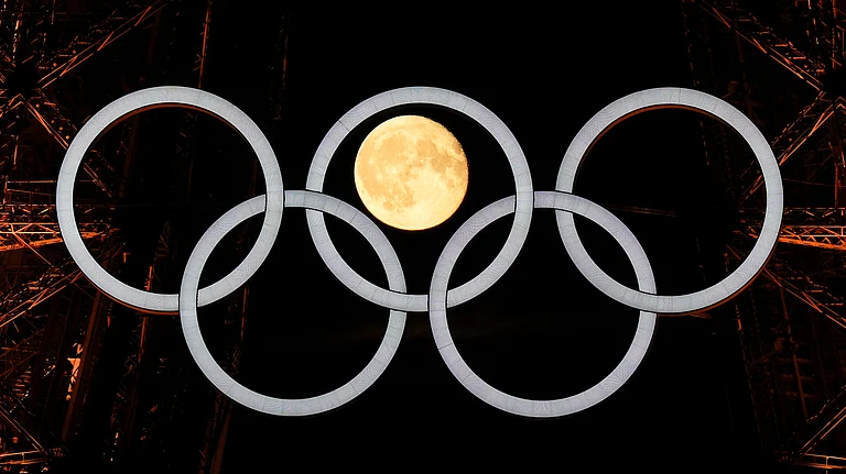 A full moon rises behind the Olympic rings hanging from the Eiffel Tower Monday, July 22, 2024, in Paris, France. The opening ceremony for the Olympic Games is Friday. - (AP Photo/David J. Phillip)