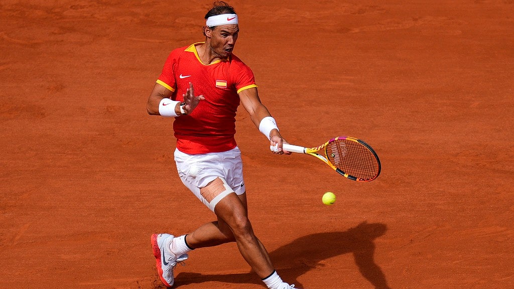 AP : Rafael Nadal of Spain returns the ball against Marton Fucsovics of Hungary during the men's singles tennis competition, at the 2024 Summer Olympics, Sunday, July 28, 2024, in Paris, France.